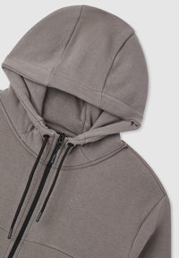 Felpa grigia con cappuccio, caratterizzata da una chiusura con zip, cappuccio regolabile e tessuto morbido e testurizzato. Include una tasca a marsupio e una silhouette rilassata.