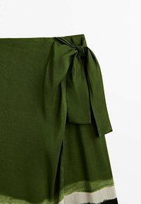 Olijfgroene rok met een strik op de taille, met een gradient zoom die overgaat in crème, gemaakt van lichte stof.