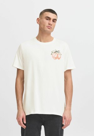Camiseta de algodón blanca con un gráfico de dos frutas naranjas con hojas verdes en el lado izquierdo del pecho. Tiene mangas cortas y un diseño de corte relajado.