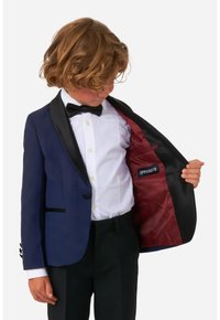 Chaqueta de esmoquin azul marino con solapas negras, forro rojo, cierre de un botón y detalle decorativo de botones en las mangas. Camisa blanca y pajarita visibles.