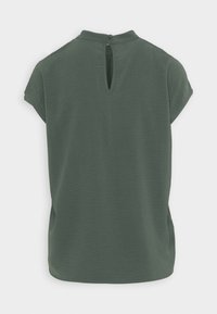 Blusa verde a maniche corte in tessuto testurizzato, con apertura a chiave sul retro e scollatura rotonda.