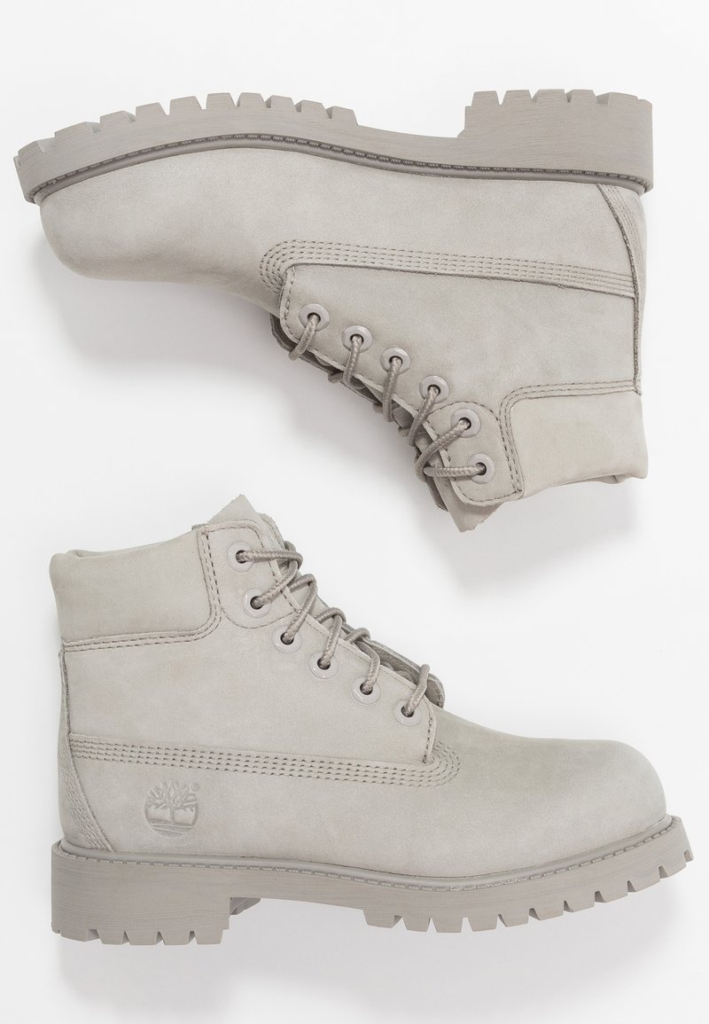 Stivali alla caviglia in suede grigio con punta arrotondata, sei asole e suola spessa scanalata. Il design include dettagli cuciti e un logo.