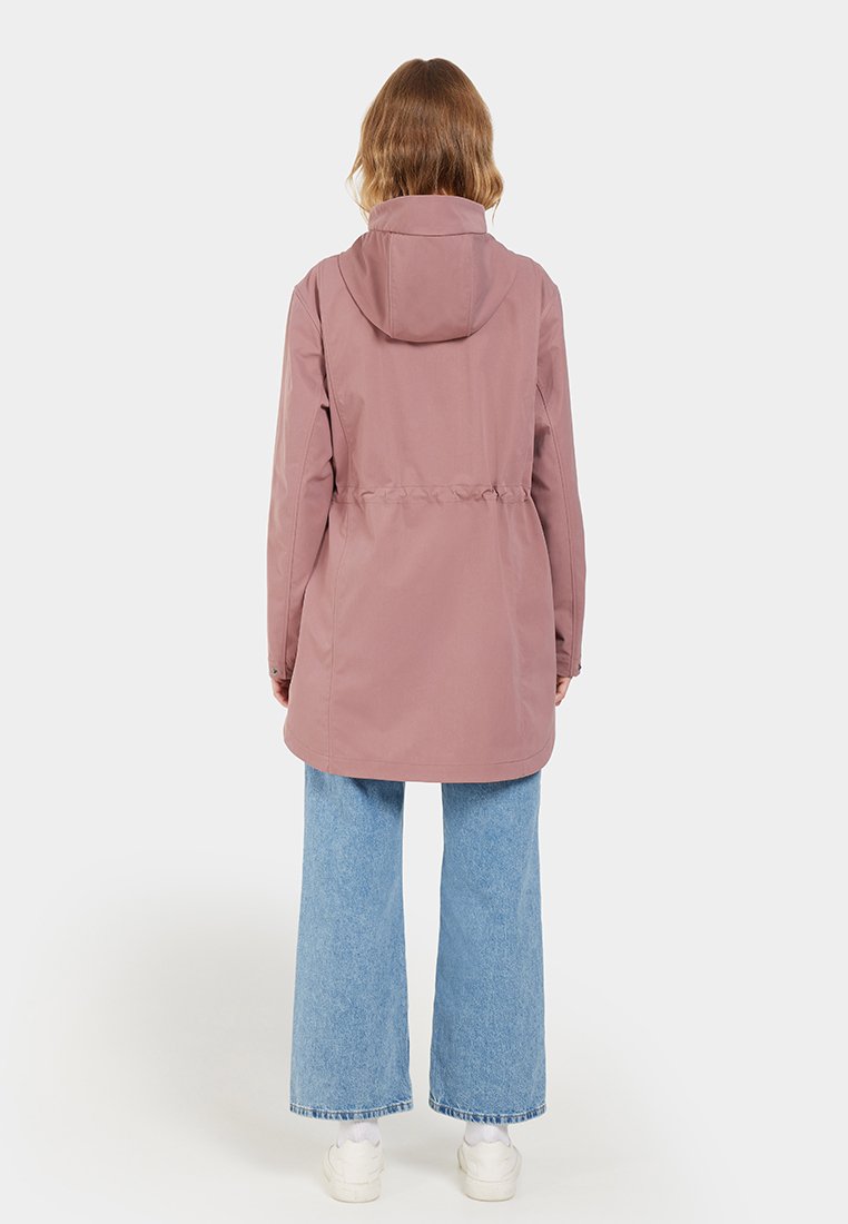 Helle rosa wasserabweisende Jacke mit Kapuze, taillierter Taille und langen Ärmeln. Kombiniert mit weiten blauen Jeans. Glatte Textur, lässiges Design.