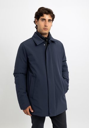 Cappotto blu navy con un design slim, colletto a risvolto, due tasche laterali e chiusura con zip e bottoni a pressione. Tessuto dalla texture liscia.