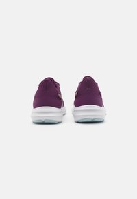Baskets de sport violettes avec une tige texturée, semelles blanches et accents réfléchissants. Tige au talon et col rembourré pour un confort supplémentaire.