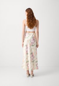 Jupe maxi florale en tissu doux et léger. Présente une palette de couleurs pastel avec des accents roses, jaunes et verts. Texture lisse et longueur jusqu'aux chevilles.