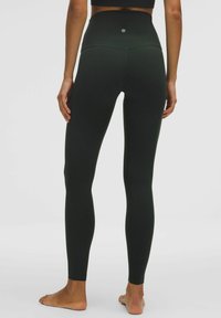 Czarne legginsy z wysokim stanem o gładkiej teksturze, dopasowanym kroju i przeszyciami, z logo umieszczonym na tylnej części pasa.