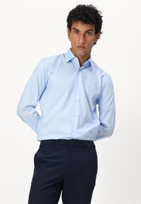 Himmelblaues langärmeliges Hemd mit Button-Down-Kragen, glatter Textur und subtiler Schimmer, kombiniert mit navyblauen Hosen.