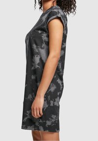 Robe T-shirt en tie-dye noir et gris avec manches courtes, coupe décontractée et texture en coton douce ; l'ourlet tombe au-dessus du genou.