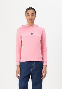 Rosa hettegensere laget av myk bomull, med logo-print foran, justerbar snorhette og ribbestrikkede mansjetter og nederkant. Brukt med denim.