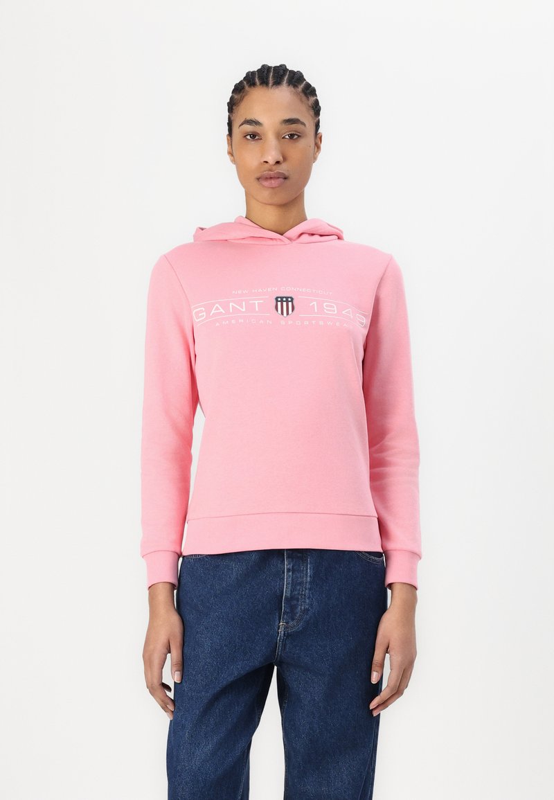 Rosa hettegensere laget av myk bomull, med logo-print foran, justerbar snorhette og ribbestrikkede mansjetter og nederkant. Brukt med denim.
