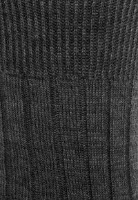 Dunkelgrauer gestrickter Stoff mit vertikalem Rippenmuster und abwechselnd breiten und schmalen Rippungen.