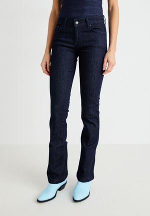 Dark blue denim jeans with a slim fit, five-pocket design, and a mid-rise waist. Paired with light blue heeled boots.