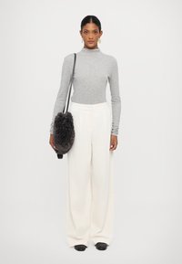 Gray long-sleeve turtleneck top, white wide-leg ribbed trousers, and a black fluffy shoulder bag. Model wearing black slip-on shoes.