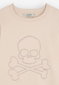 Sudadera de cuello redondo en color beige claro, con un diseño en relieve de calavera y tibias cruzadas en hilo contrastante. Tejido suave de mezcla de algodón.
