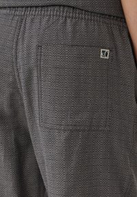 Grijze geweven stoffen broek met een achterzak en subtiel patroon. Inclusief een klein label met het nummer "5.0" erop genaaid.