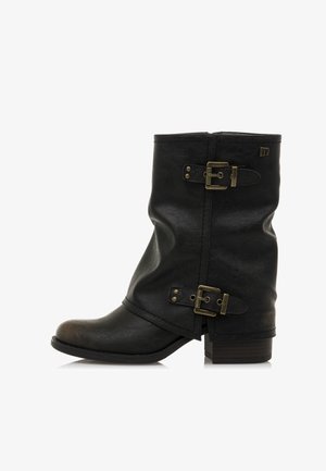 Stivale in pelle nera a metà polpaccio con due fibbie in ottone e un tacco basso impilato, suola angolata e leggero design sformato.