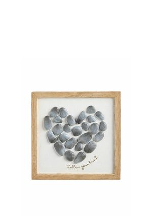 Szare kamienie ułożone w kształt serca na białym płótnie w drewnianej ramie z napisem "Follow your heart" poniżej kamieni.
