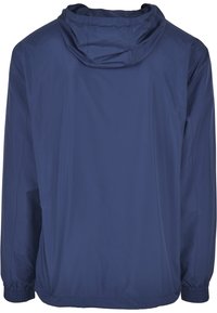 Veste légère bleu marine avec capuche, poignets élastiques et tissu lisse et résistant à l'eau, au design simple.