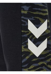 Schwarze Leggings mit einem texturierten blau-grünen Camouflagemuster an der Seite, akzentuiert durch zwei weiße Chevronformen.