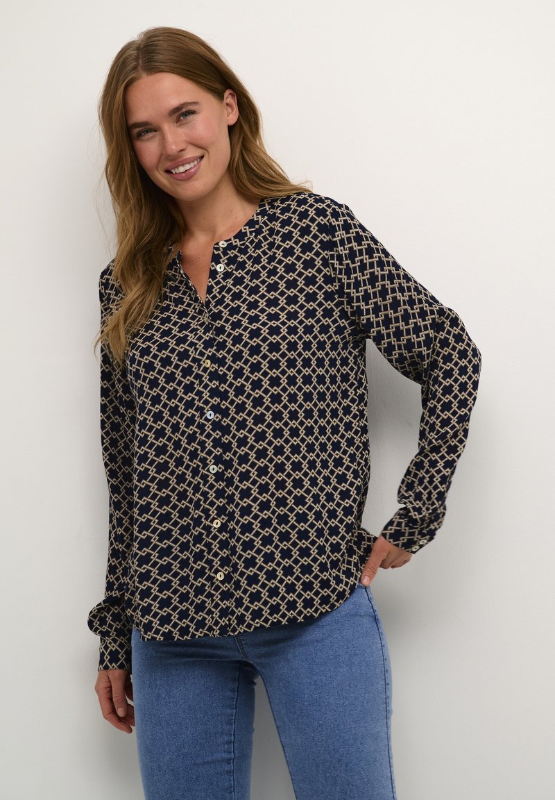 Camicia blu navy con bottoni, motivo geometrico beige, maniche lunghe e colletto alla mandarino. Realizzata in tessuto leggero.
