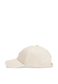 Baseball cap in beige fabric, featuring a curved brim, embroidered logo detail on the side, and adjustable strap at the back.