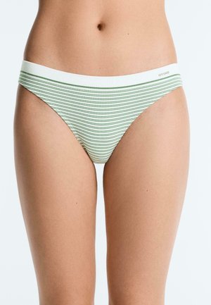 Femeie purtând lenjerie de tip bikini în dungi albe și verzi, cu talie joasă, bandă îngustă în talie și logo mic de marcă pe lateral.