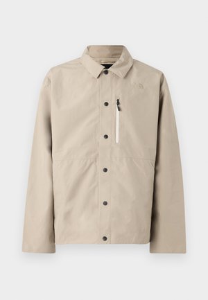 Beež North Face nööpidega jakk, millel on krae ja tõmblukuga rinnatasku, loodud välitingimustes kandmiseks.