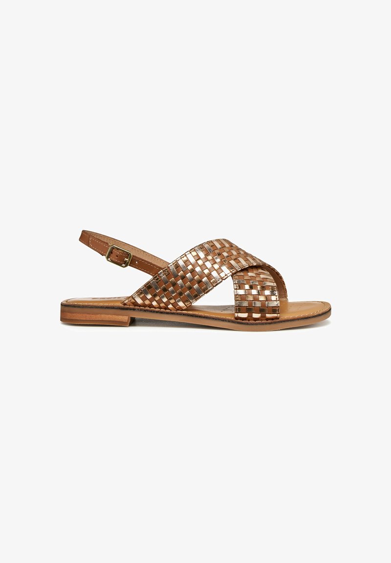 Sandale plate avec des brides en cuir tressé métallisé croisées sur le pied et une bride de cheville réglable avec boucle.