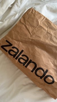 Brown paper bag with visible creases and folds, featuring a large black "zalando" logo printed on the side.