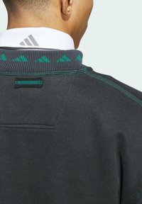 Maglione grigio scuro con colletto testurizzato e dettagli in teal, cuciture a contrasto e un piccolo anello di sospensione sul retro.