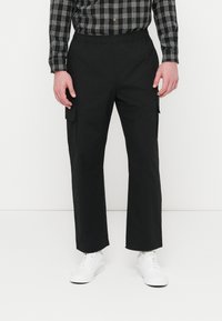 Pantalon cargo noir avec une taille élastique, des poches latérales et une coupe droite. Confectionné dans un tissu lisse à finition mate.