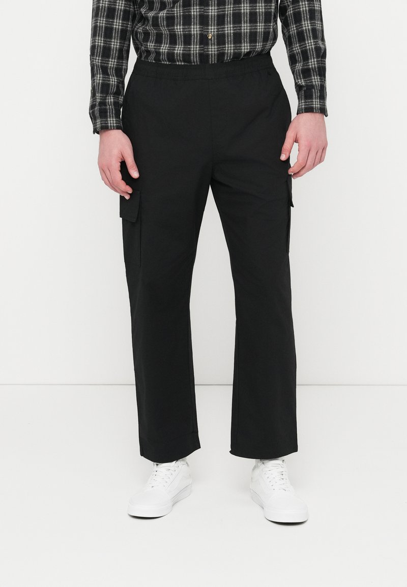 Pantalon cargo noir avec une taille élastique, des poches latérales et une coupe droite. Confectionné dans un tissu lisse à finition mate.