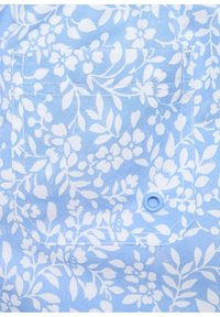 Světle modrá látka s bílým květinovým vzorem; obsahuje náprsní kapsu a modrý knoflík na dnu kapsy. Hladký povrch.