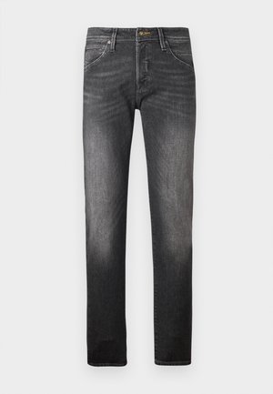 Tumedates denim püksid kitseneva lõikega, millel on nupp ja zipp-fliis, traditsiooniline viie tasku disain ning peene kulumisjälg jalgadel.