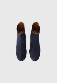 Navy blue suede ankle boots with a smooth texture, rounded toe, and slip-on design. Interior features brown leather lining.