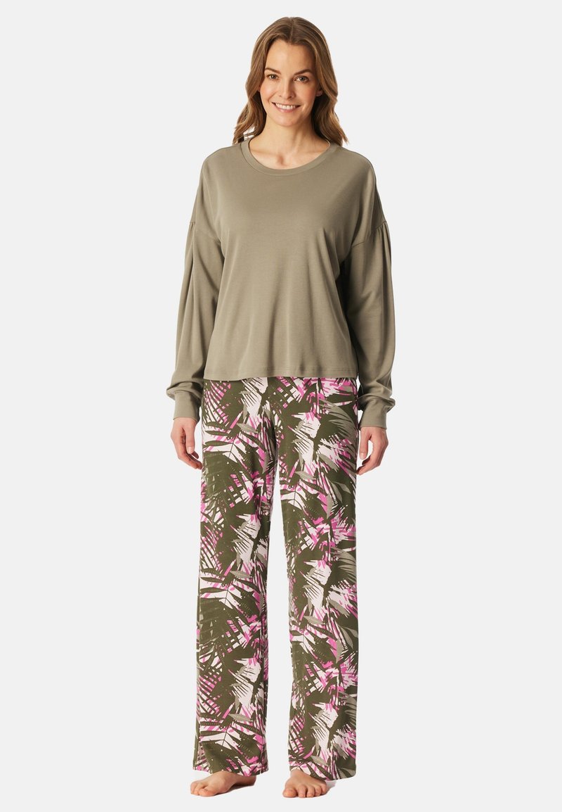 Szary, długi rękaw, zestawiony z luźnymi zielonymi spodniami do piżamy z różowym i białym abstrakcyjnym wzorem, boso na jednolitym tle.