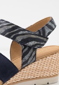 Klínové sandály s modrou nubukovou základnou a vzorovaným námořnickým a šedým zebra potiskem na pásku. Přírodní pletená juta jako platforma s gumovou podrážkou.