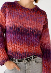Flerfärgad stickad tröja med en gradient av röda, orange, lila och blå nyanser. Ribbad textur och långa ärmar. I kombination med ett svart nitat bälte.