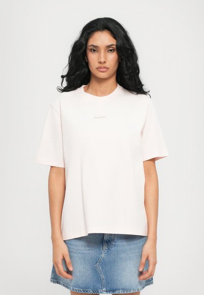Light pink cotton t-shirt with short sleeves, a round neckline, and a small logo detail in the center. Soft texture and relaxed fit.