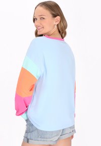 Farbenfrohes Langarmshirt mit blauem Körper und ärmeln in Orange, Pink und Mintfarben. Glattes Material mit lockerer Passform und rundem Halsausschnitt.