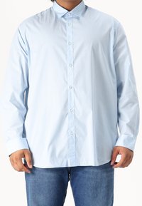 Camicia azzurro chiaro con bottoni, realizzata in tessuto liscio, con colletto appuntito, maniche lunghe e chiusura frontale con bottoni standard.