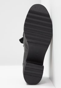 Semelle de chaussure en cuir noir avec une finition texturée ; présente un motif épais et strié pour l'adhérence et un talon plat. Taille marquée comme 37.