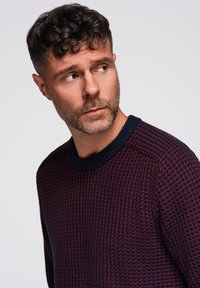 Neulepaita tummansinisessä ja burgundin värisessä pinnassa, jossa on ribattu pyöreä kaula-aukko ja rakenne, jossa on tiheä kudonta.