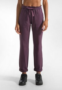 Pantaloni viola, larghi e comodi, con vita elastica, cordoncino e due tasche frontali. Polsini arrotolati e un tessuto morbido e testurizzato.
