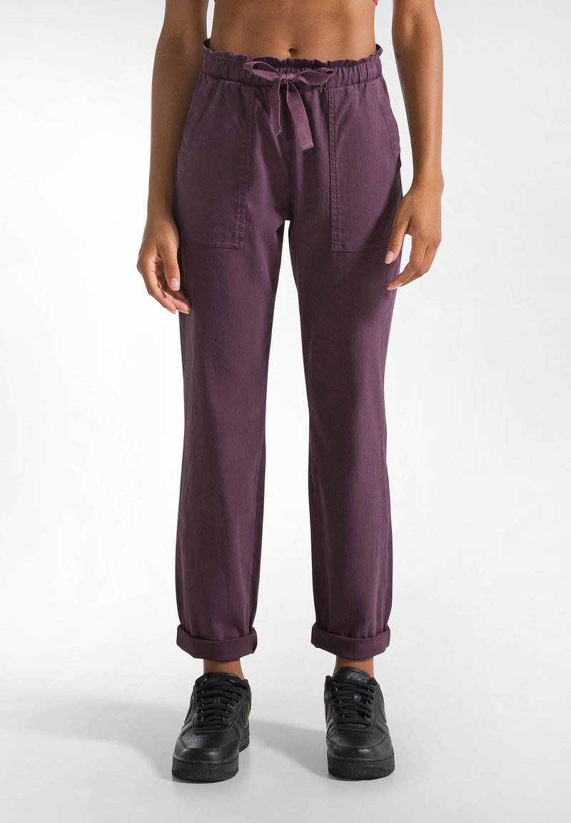 Pantaloni viola, larghi e comodi, con vita elastica, cordoncino e due tasche frontali. Polsini arrotolati e un tessuto morbido e testurizzato.
