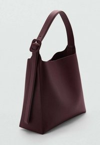 Sac à main en cuir bordeaux foncé avec une large sangle et une boucle réglable, présentant un design minimaliste et structuré.