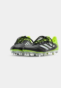 Black and neon green soccer cleats with a smooth upper, black laces, three white stripes, and a transparent multi-stud sole.