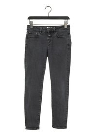 Jeans skinny de color gris oscuro exhibidos en un perchero negro. Presenta un diseño clásico de cinco bolsillos, botón de metal y un ligero desgastado en la tela.