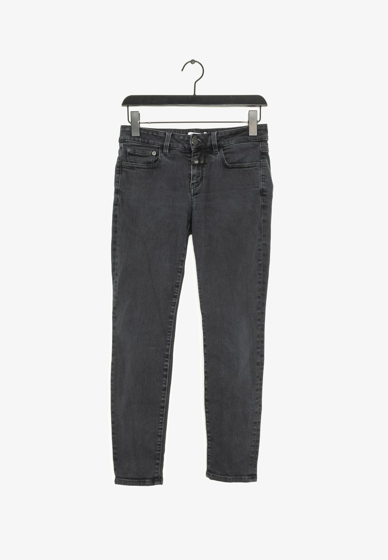 Jeans skinny de color gris oscuro exhibidos en un perchero negro. Presenta un diseño clásico de cinco bolsillos, botón de metal y un ligero desgastado en la tela.
